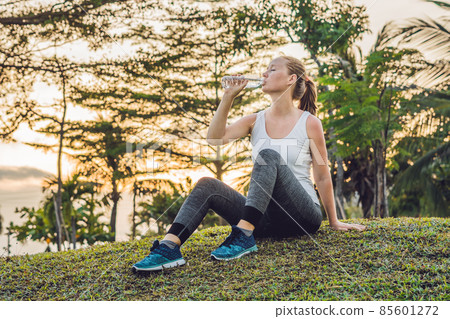 Sporty woman drinking water outdoor on sunny day Sporty woman drinking water outdoor on sunny day 85601272
