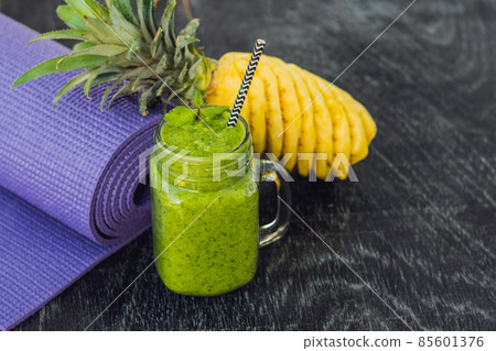 Green smoothies made of spinach and pineapple and a yoga mat. Healthy eating and sports concept 85601376