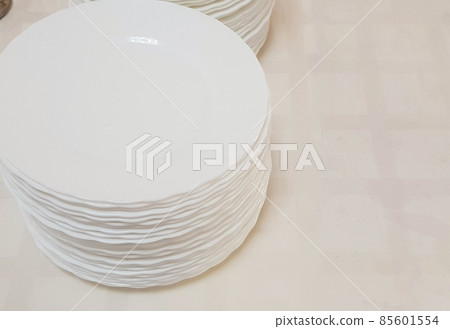 White clean empty plates in a stack on the table, service in the hotel cafe White clean empty plates in a stack on the table, service in the hotel cafe 85601554