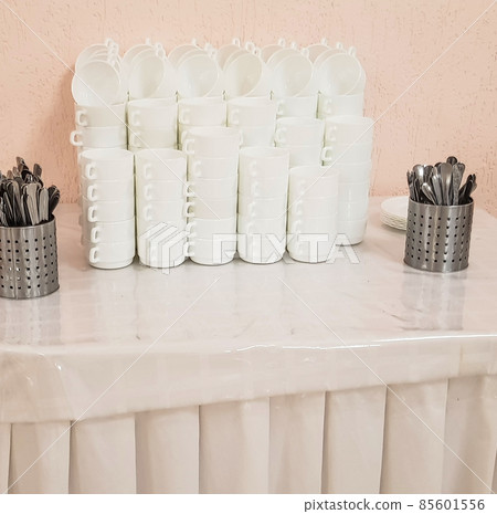 White clean empty soup plates in a stack and cutlery on the table, service in the hotel cafe 85601556