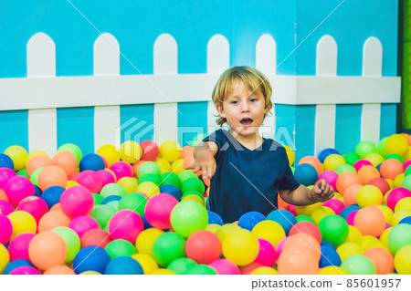 Happy little kid boy playing at colorful plastic balls playground high view. Funny child having fun indoors Happy little kid boy playing at colorful plastic balls playground high view. Funny child having fun indoors 85601957