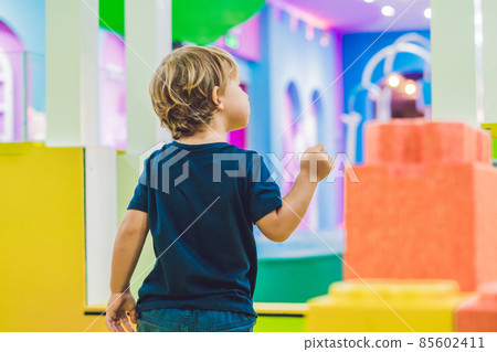 Happy boy playing indoors with big plastic construction blocks 85602411