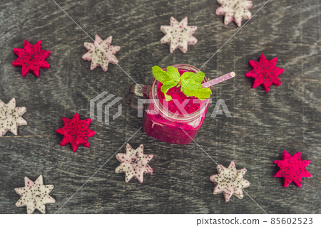 Pieces of sliced dragon fruit in the form of a star and smoothies from a dragon fruit on an old withered background Pieces of sliced dragon fruit in the form of a star and smoothies from a dragon fruit on an old withered background 85602523