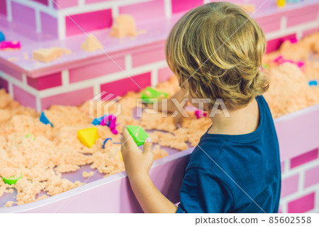 Boy playing with kinetic sand in preschool. The development of fine motor concept. Creativity Game concept Boy playing with kinetic sand in preschool. The development of fine motor concept. Creativity Game concept 85602558