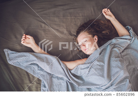 Beautiful young woman lying down in bed and sleeping, top view. Do not get enough sleep concept Beautiful young woman lying down in bed and sleeping, top view. Do not get enough sleep concept 85602896