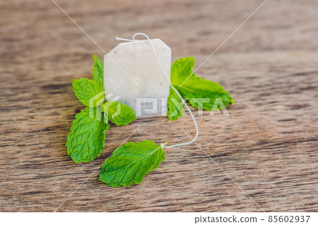 Tea bags on wooden background with fresh melissa, mint. Tea with mint concept Tea bags on wooden background with fresh melissa, mint. Tea with mint concept 85602937