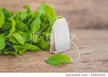 Tea bags on wooden background with fresh melissa, mint. Tea with mint concept 85603093