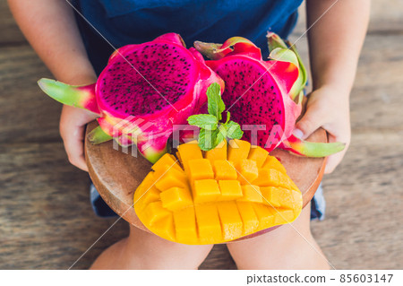 Diced dragon fruit and mango in the hands of the boy Diced dragon fruit and mango in the hands of the boy 85603147