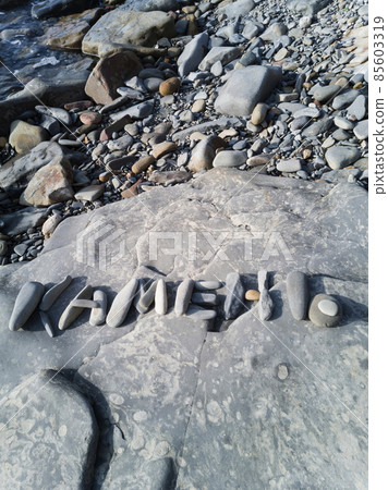 On a large stone on the seashore, the inscription "Stone" is laid out in Russian letters On a large stone on the seashore, the inscription "Stone" is laid out in Russian letters 85603319
