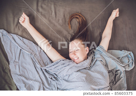 Beautiful young woman lying down in bed and sleeping, top view. Do not get enough sleep concept 85603375