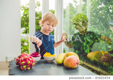 Little cute boy eating mango on the terrace Little cute boy eating mango on the terrace 85603454