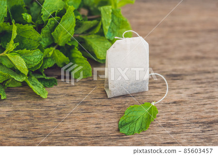Tea bags on wooden background with fresh melissa, mint. Tea with mint concept 85603457