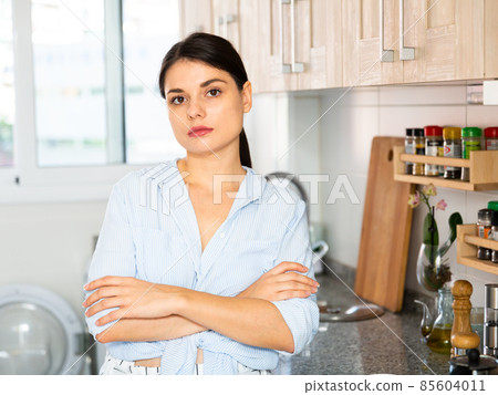 Portrait of brunette arms crossed woman in kitchen Portrait of brunette arms crossed woman in kitchen 85604011