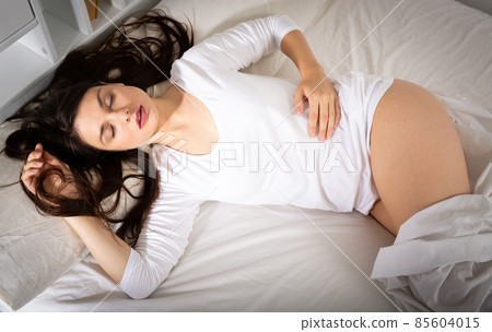 Young woman in white sleepwear sleeping in bed in home Young woman in white sleepwear sleeping in bed in home 85604015