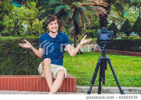 Young man blogger records video in front of the camera in the park Young man blogger records video in front of the camera in the park 85605036