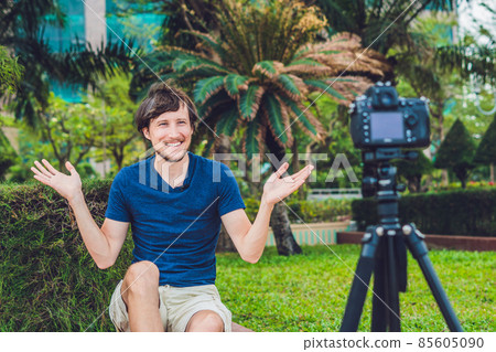 Young man blogger records video in front of the camera in the park Young man blogger records video in front of the camera in the park 85605090