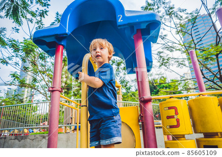 Happy little kid boy playing at colorful playground. Adorable child having fun outdoors Happy little kid boy playing at colorful playground. Adorable child having fun outdoors 85605109