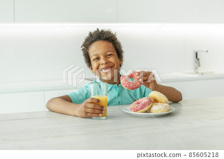 Laughing kid boy with orange juice and donuts Laughing kid boy with orange juice and donuts 85605218