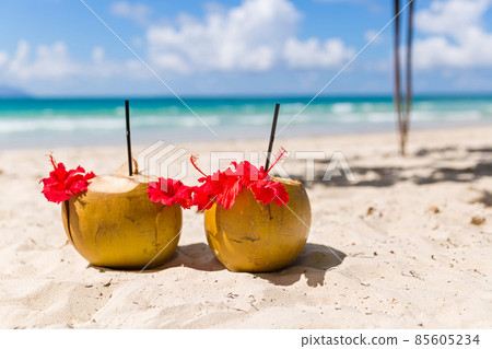 Two coconut cocktails on white sand beach 85605234