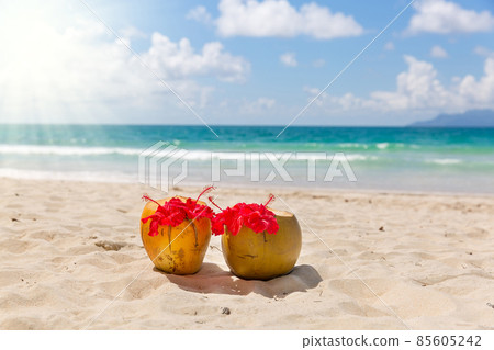 Two coconut cocktails on white sand beach 85605242