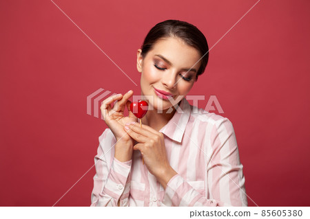 Cheerful smiling woman with heart shape on red Cheerful smiling woman with heart shape on red 85605380