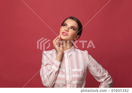 Attractive brunette woman looking up on red banner background 85605382