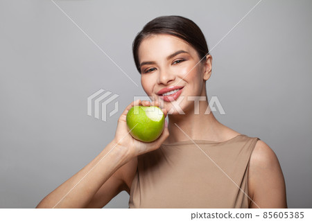 Attractive model woman biting green apple on white background Attractive model woman biting green apple on white background 85605385