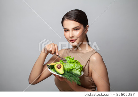 Woman holding green vegetables avocado and green herbs on plate. Healthy eating and diet concept Woman holding green vegetables avocado and green herbs on plate. Healthy eating and diet concept 85605387