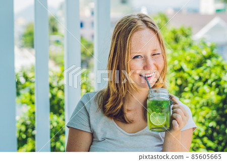 A young woman holds a mason jar in her hand with a mojito. Spring drink concept 85605665