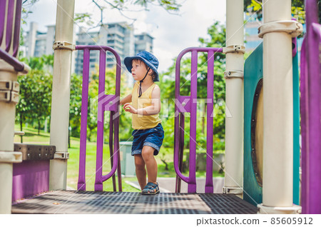 Happy little kid boy playing at colorful playground. Adorable child having fun outdoors 85605912