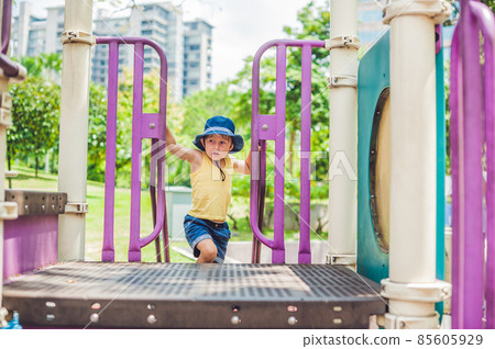 Happy little kid boy playing at colorful playground. Adorable child having fun outdoors Happy little kid boy playing at colorful playground. Adorable child having fun outdoors 85605929
