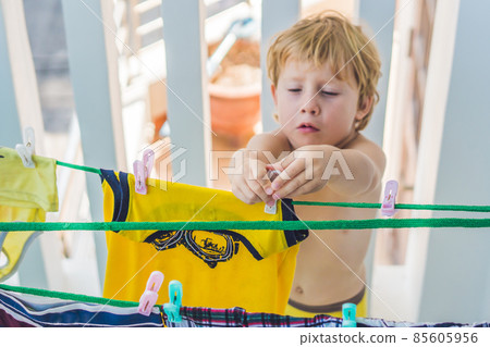 A little boy helps her mother to hang up clothes A little boy helps her mother to hang up clothes 85605956