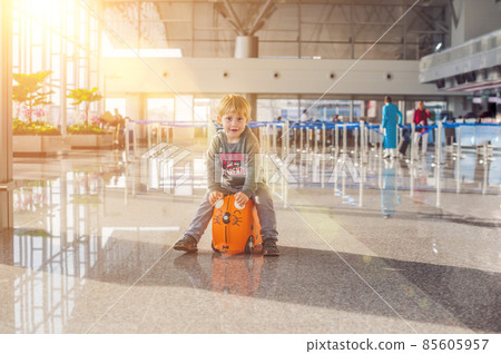 Cute little boy with orange suitcase at airport Cute little boy with orange suitcase at airport 85605957