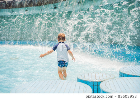 Boy playing in the paddling pool in the summertime Boy playing in the paddling pool in the summertime 85605958