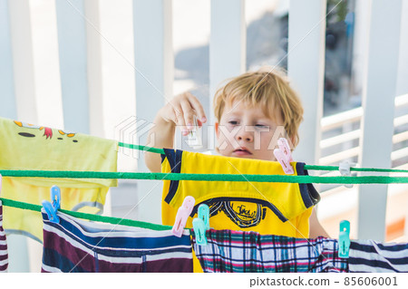 A little boy helps her mother to hang up clothes 85606001