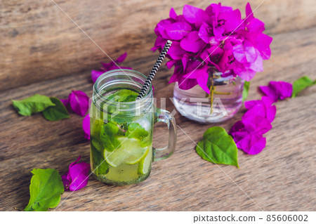 Spring purple flowers and spring mojito drink on an old wooden background Spring purple flowers and spring mojito drink on an old wooden background 85606002