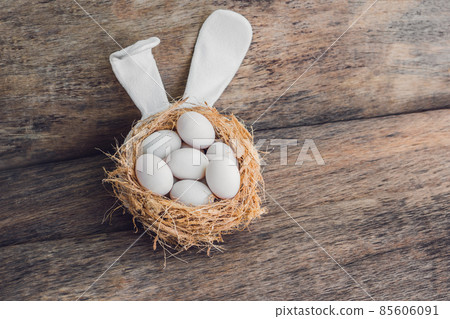 A nest with three white Easter eggs and bunny ears at home on Easter day. Celebrating Easter at spring. Painting eggs A nest with three white Easter eggs and bunny ears at home on Easter day. Celebrating Easter at spring. Painting eggs 85606091