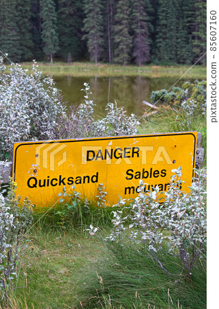 A danger quicksand sign with a pond in the background 85607160