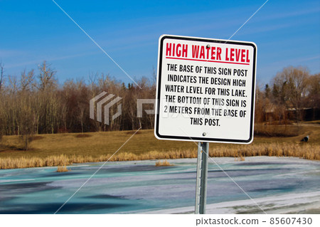 High water level sign along a storm drainage pond 85607430