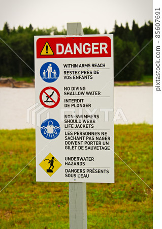 A beach danger sign with rules in both english and french A beach danger sign with rules in both english and french 85607691