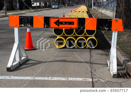 A construction barrier sign with pipes on the road A construction barrier sign with pipes on the road 85607717
