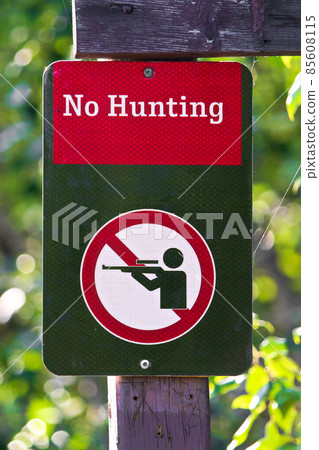Closeup of a no hunting sign on a green background 85608115