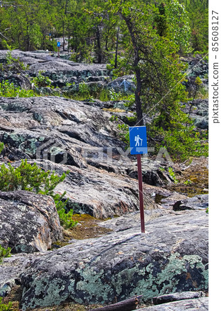 A blue hiking trail sign over rough rocks A blue hiking trail sign over rough rocks 85608127