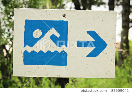 A blue beach beach sign with a direction arrow 85609041