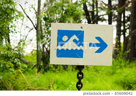 A blue beach beach sign with a direction arrow 85609042