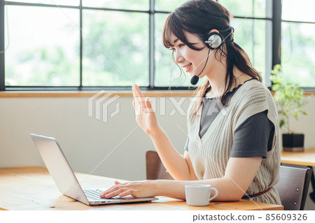 A woman wearing a headset and using a computer 85609326