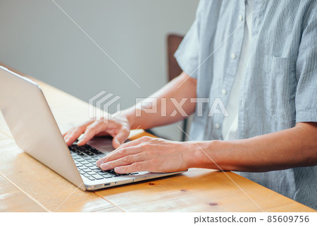 A man using a personal computer (without a face) 85609756