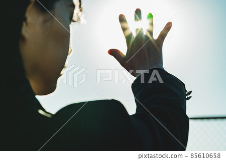 High school girl holding her hand over the sun High school girl holding her hand over the sun 85610658