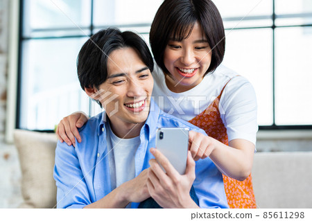 A young couple looking at a smartphone in the living room 85611298
