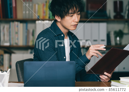 A man writing in front of a computer 85611772